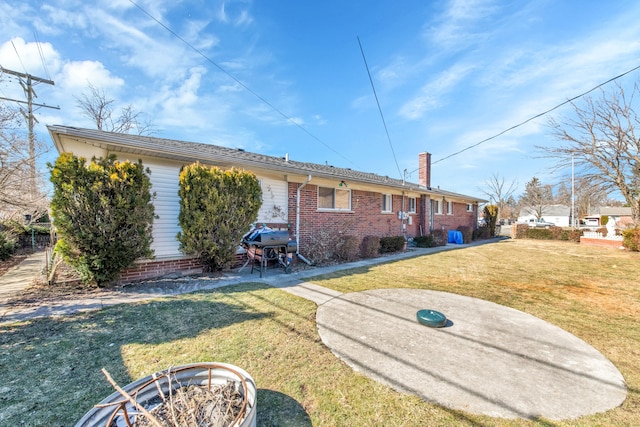 view of front of property featuring brick siding, a chimney, and a front yard