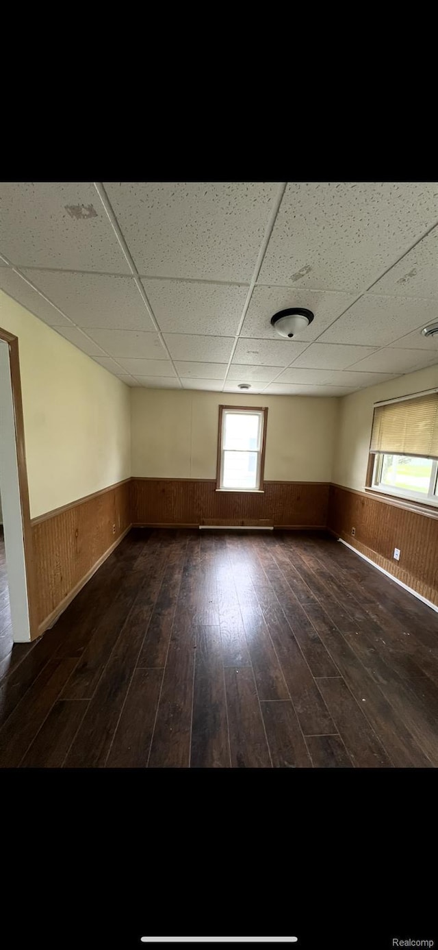 1531 Gilbert St, Saginaw, MI 48602 - spare room featuring a drop ceiling, a wainscoted wall, and dark wood-style floors