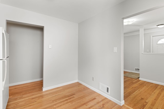 spare room with light wood-style flooring, visible vents, and baseboards