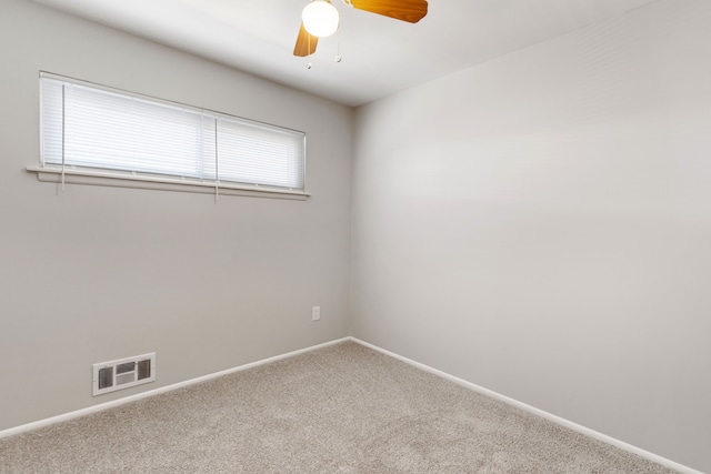 carpeted empty room with baseboards, visible vents, and ceiling fan