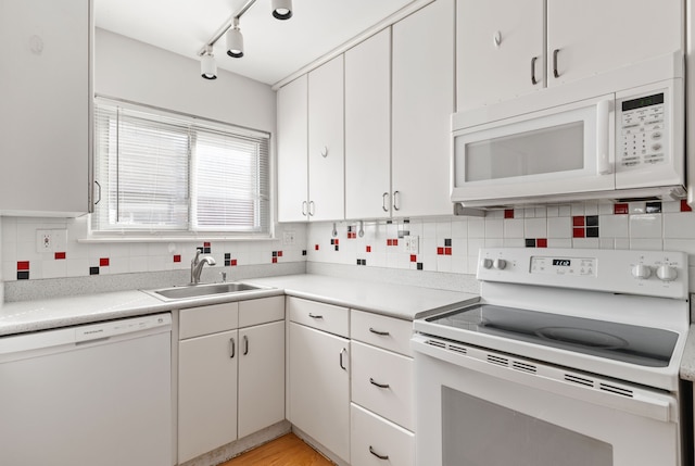 kitchen with white appliances, a sink, white cabinets, light countertops, and tasteful backsplash