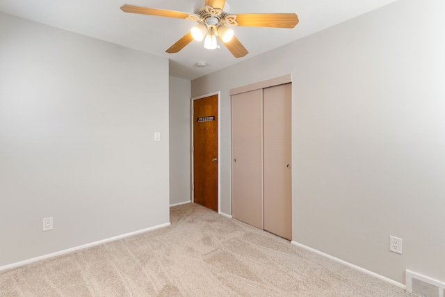 unfurnished bedroom with a closet, visible vents, light carpet, ceiling fan, and baseboards