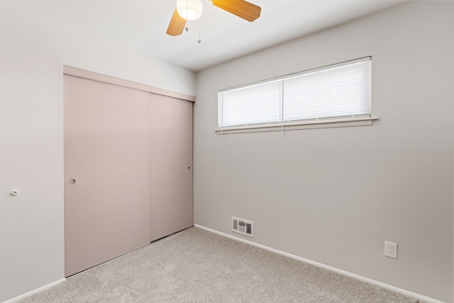 unfurnished bedroom featuring baseboards, visible vents, a ceiling fan, light colored carpet, and a closet