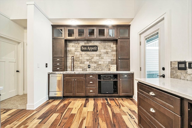 bar with baseboards, a sink, light wood-style flooring, and decorative backsplash