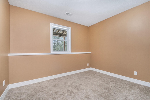 empty room featuring carpet floors, visible vents, and baseboards