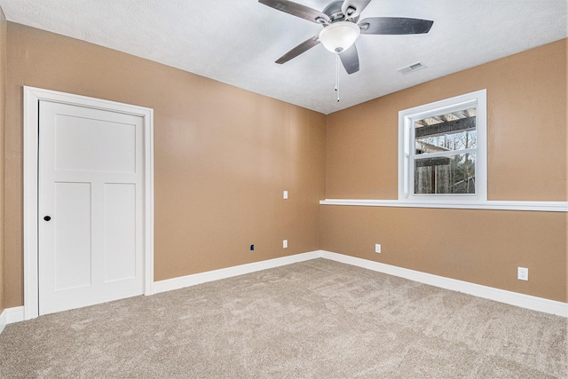 carpeted spare room with a ceiling fan, visible vents, and baseboards