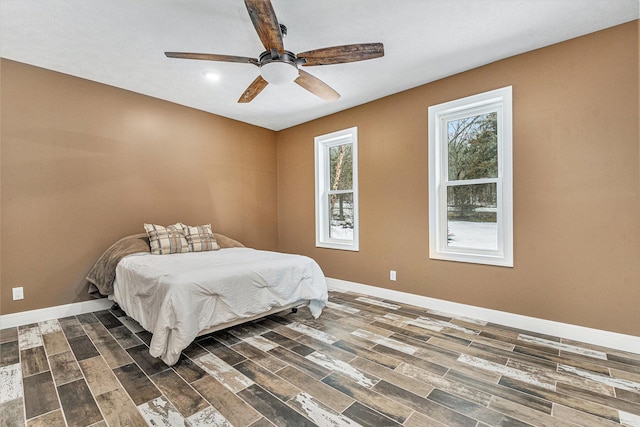 bedroom with a ceiling fan, baseboards, and dark wood-style flooring