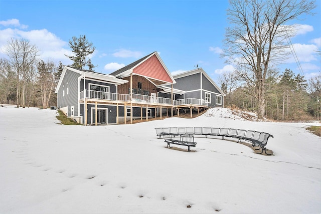 snow covered rear of property with stairs and a wooden deck