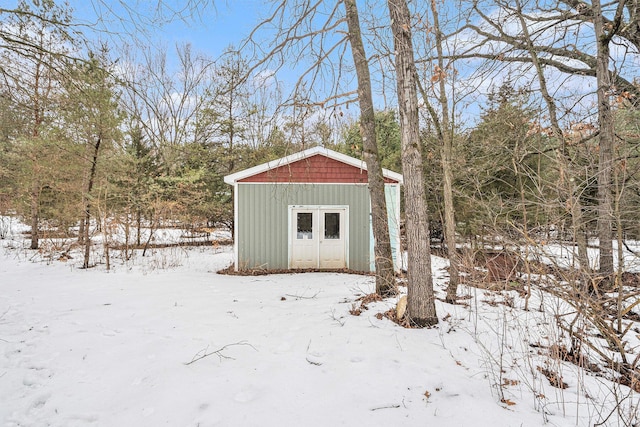 snow covered structure featuring an outbuilding and a storage shed