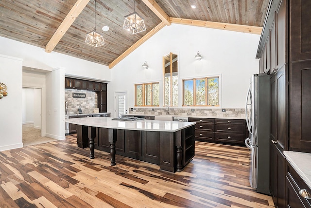 kitchen featuring wooden ceiling, backsplash, beamed ceiling, freestanding refrigerator, and a sink