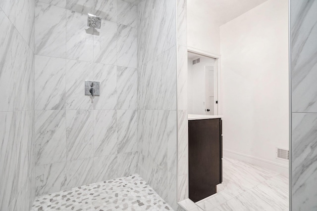 full bath featuring tiled shower, vanity, visible vents, and baseboards