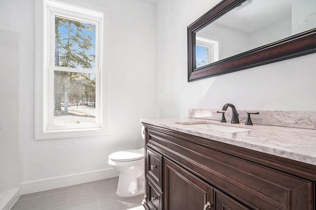 bathroom with toilet, vanity, and baseboards