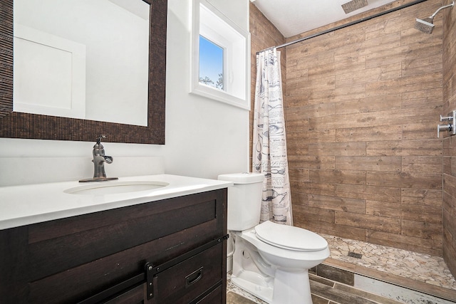 full bath with a tile shower, vanity, and toilet