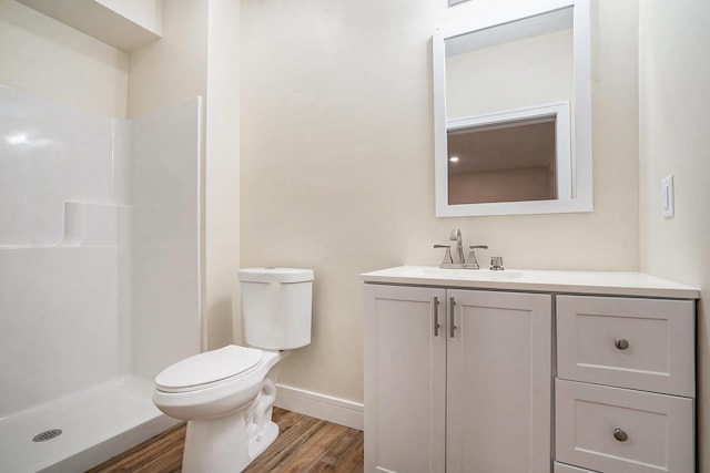 full bath featuring a shower, toilet, vanity, wood finished floors, and baseboards