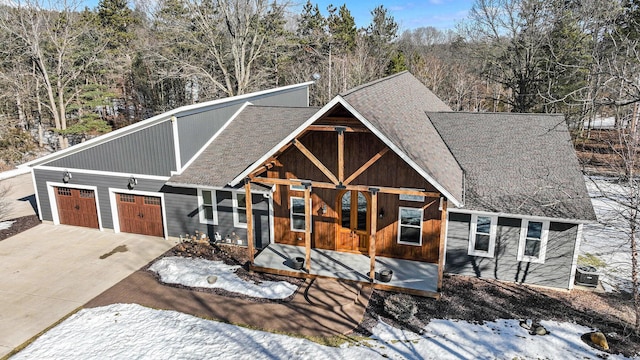 rustic home with concrete driveway, roof with shingles, and an attached garage