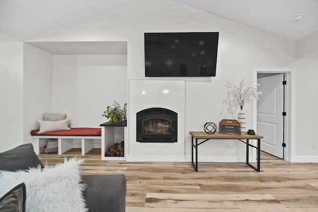 7450 Sears Rd, Horton, MI 49246 - living area with baseboards, vaulted ceiling, a tiled fireplace, and wood finished floors