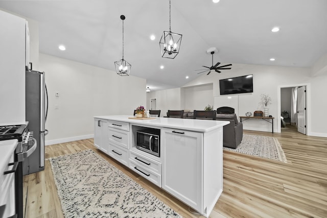 7450 Sears Rd, Horton, MI 49246 - kitchen with lofted ceiling, stainless steel appliances, white cabinets, light countertops, and light wood finished floors