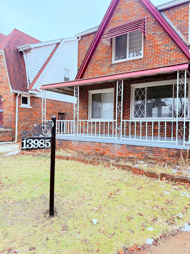 exterior space featuring a porch, a front yard, and brick siding