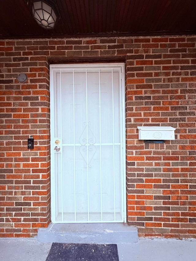 view of exterior entry featuring brick siding