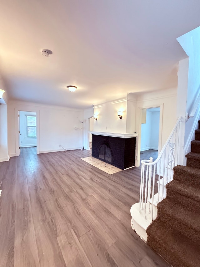 living area with baseboards, wood finished floors, stairs, crown molding, and a fireplace