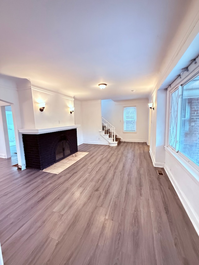 unfurnished living room with stairway, wood finished floors, visible vents, and baseboards