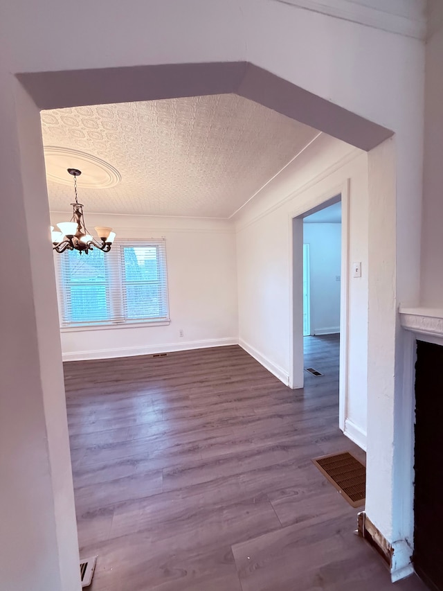 interior space with visible vents, dark wood finished floors, ornamental molding, a textured ceiling, and a chandelier