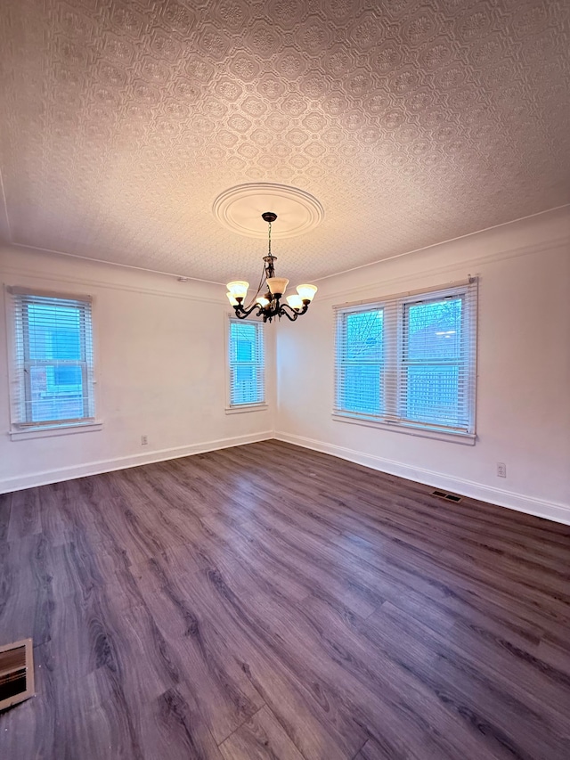 unfurnished dining area with a textured ceiling, visible vents, a chandelier, and dark wood-style flooring