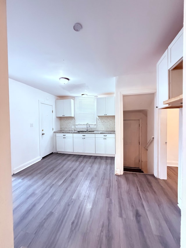 kitchen featuring tasteful backsplash, white cabinets, a sink, and wood finished floors