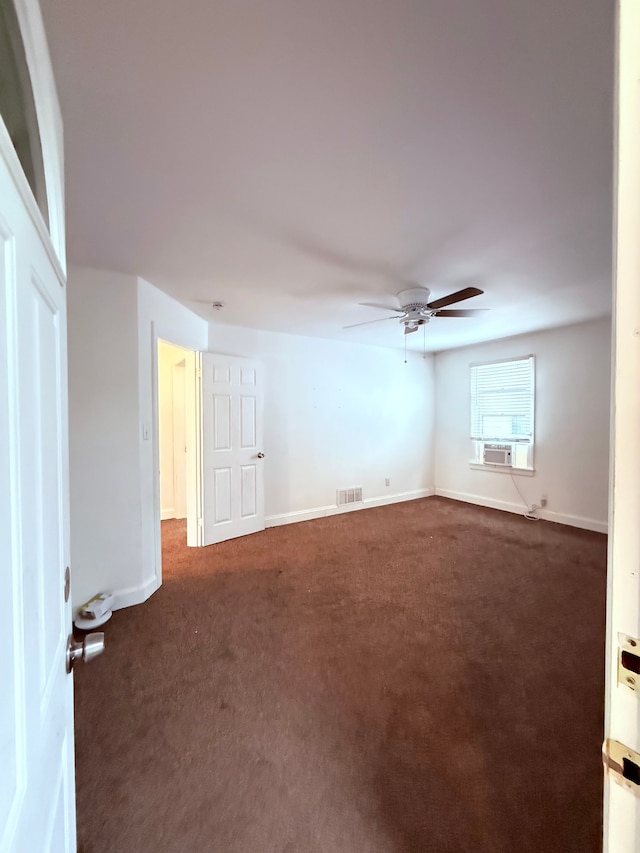 spare room featuring a ceiling fan, visible vents, dark carpet, and baseboards