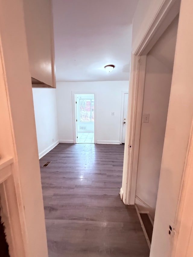 corridor with dark wood finished floors, visible vents, and baseboards