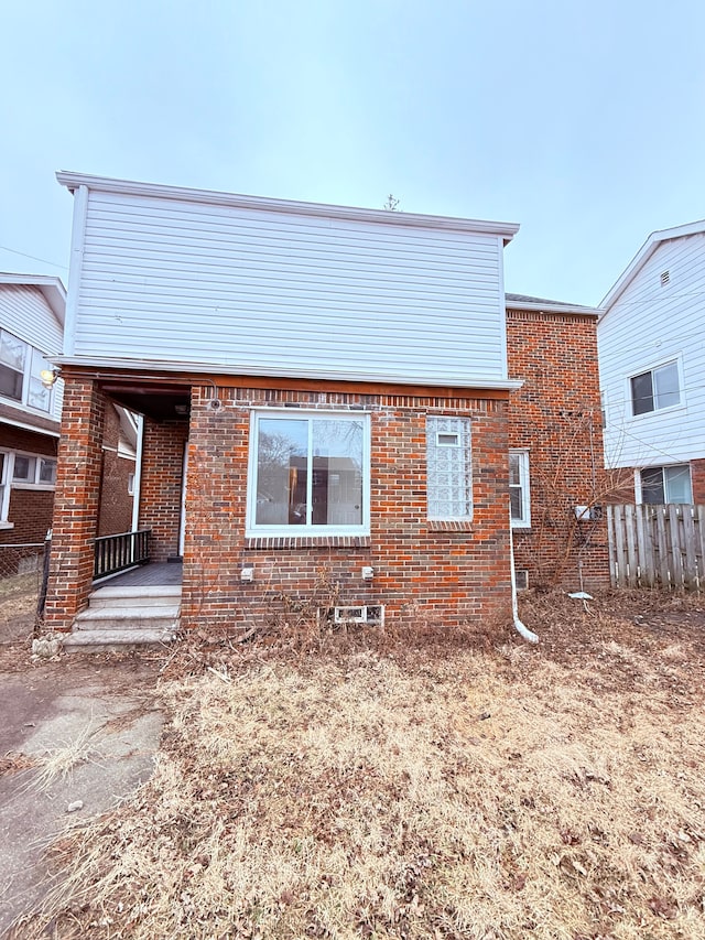 back of property featuring brick siding and fence