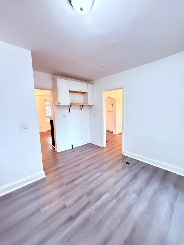 unfurnished living room with visible vents, baseboards, and wood finished floors