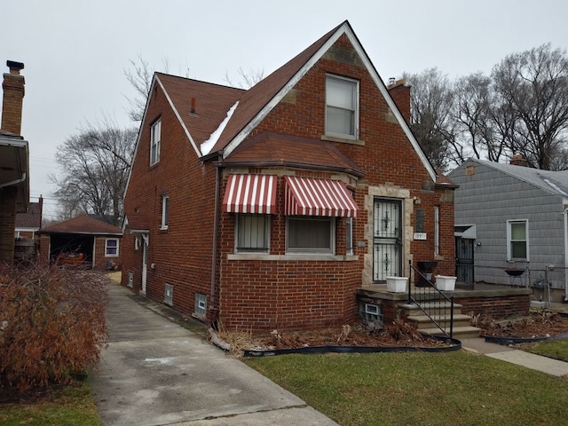 view of front of home with a chimney and brick siding