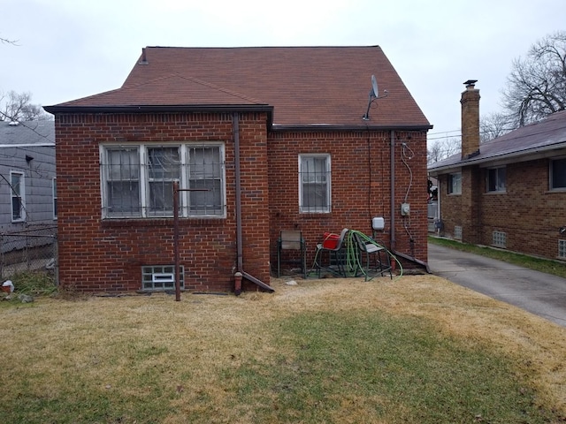 rear view of house featuring a yard and brick siding