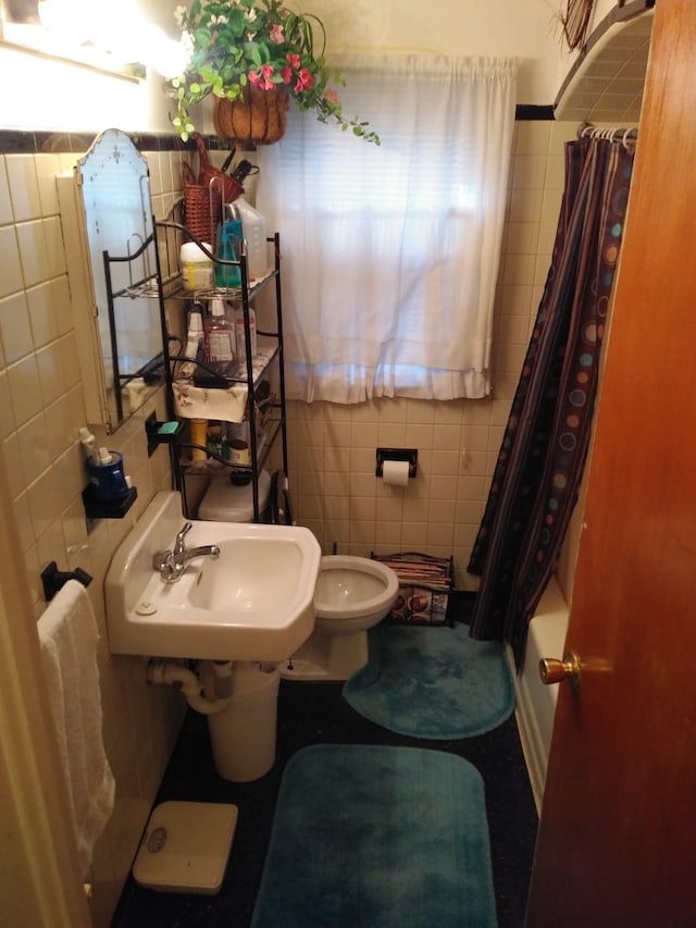 bathroom featuring a sink, tile walls, and toilet