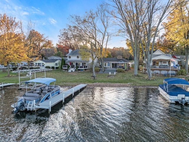 view of dock with a residential view, a water view, a yard, and boat lift