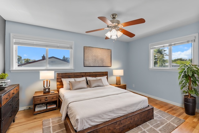 bedroom with a ceiling fan, light wood-style flooring, and baseboards