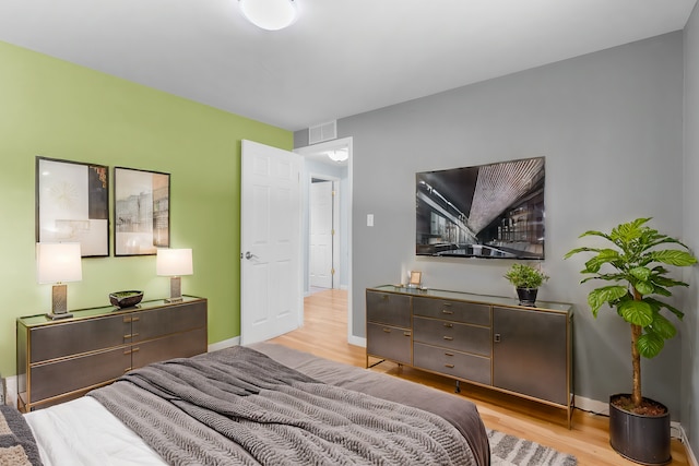 bedroom featuring baseboards, visible vents, and wood finished floors