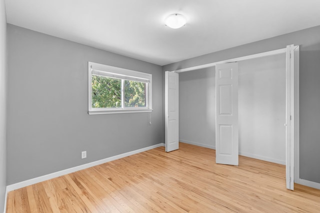 unfurnished bedroom with a closet, light wood-type flooring, and baseboards