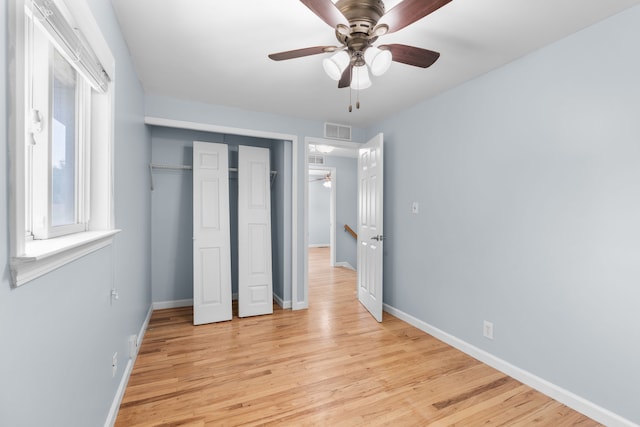 unfurnished bedroom with a closet, visible vents, light wood-style flooring, ceiling fan, and baseboards