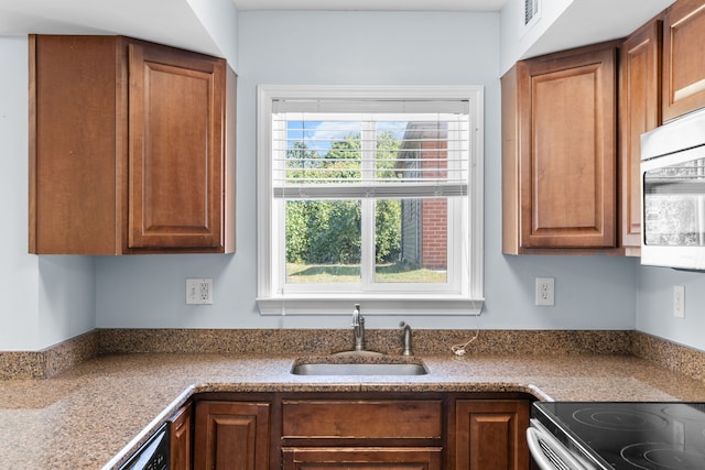 34134 Dequindre Rd, Sterling Heights, MI 48310 - kitchen with a sink, stainless steel microwave, brown cabinetry, and range with electric cooktop