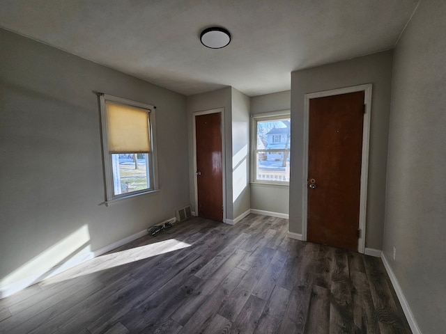 interior space with dark wood-type flooring, visible vents, and baseboards