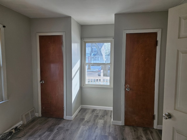 foyer entrance with visible vents, baseboards, and wood finished floors