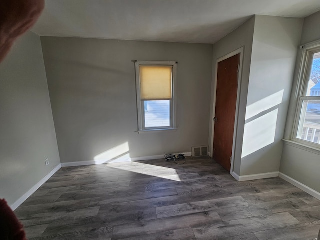 interior space featuring baseboards, wood finished floors, visible vents, and a healthy amount of sunlight