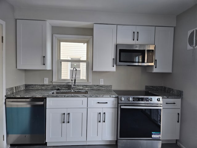 kitchen featuring appliances with stainless steel finishes, white cabinets, and a sink