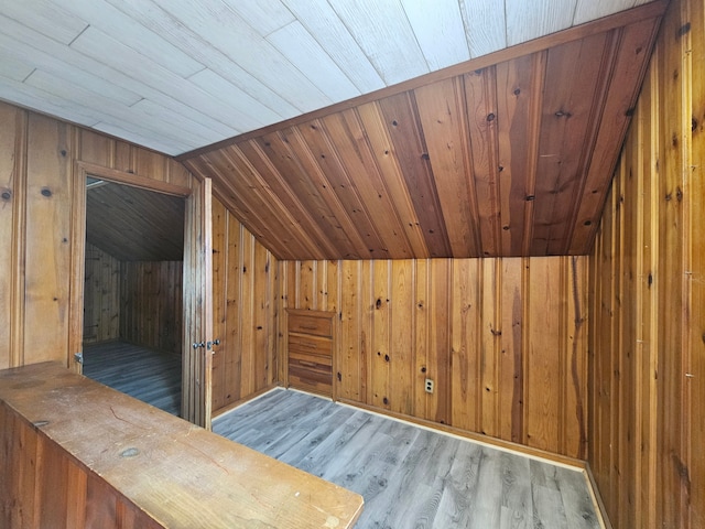 bonus room with lofted ceiling, wood walls, and wood finished floors