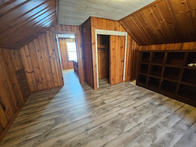 additional living space featuring lofted ceiling, wooden walls, and wood finished floors