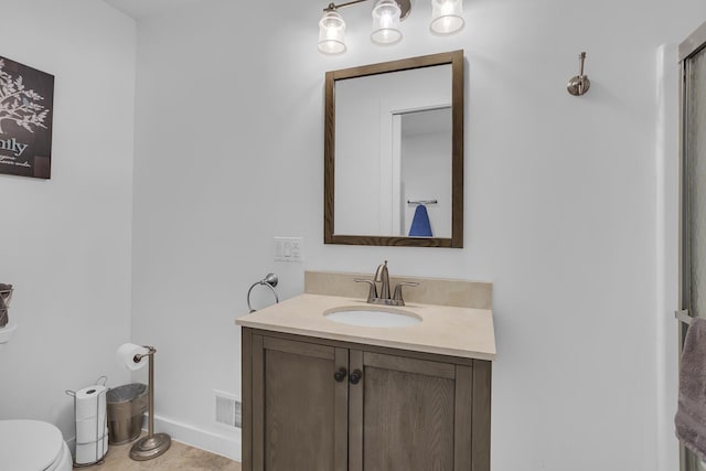 bathroom with visible vents, vanity, toilet, and baseboards