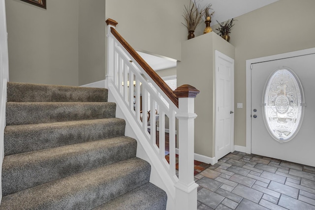 foyer with stone finish flooring, baseboards, and stairs