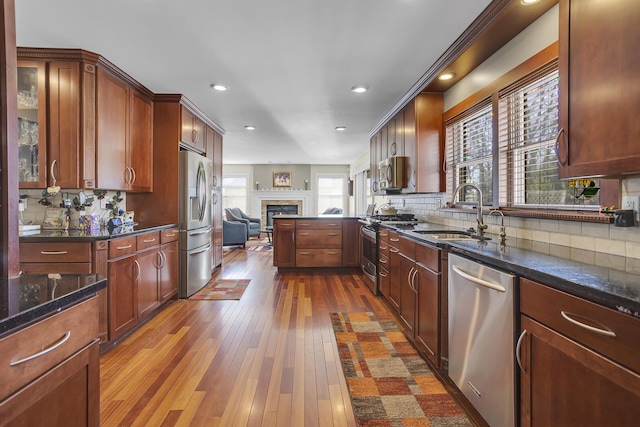 kitchen featuring dark wood-style floors, stainless steel appliances, tasteful backsplash, open floor plan, and a sink